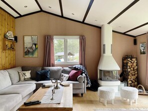 Un salon avec un canapé, une table basse, une cheminée et une fenêtre avec des rideaux.