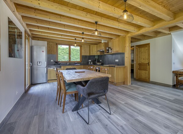 A modern kitchen with wooden beams, a central island, and pendant lighting. - 🏡 La Cabane à Camillo – Warm and Cozy Retreat (CHEVALINE)