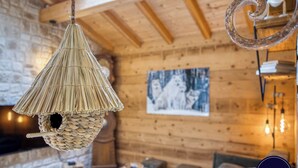 A rustic interior with a woven hanging light fixture, wooden walls, and a framed picture on the wall. - 🏡 La Cabane à Camillo – Warm and Cozy Retreat (CHEVALINE)
