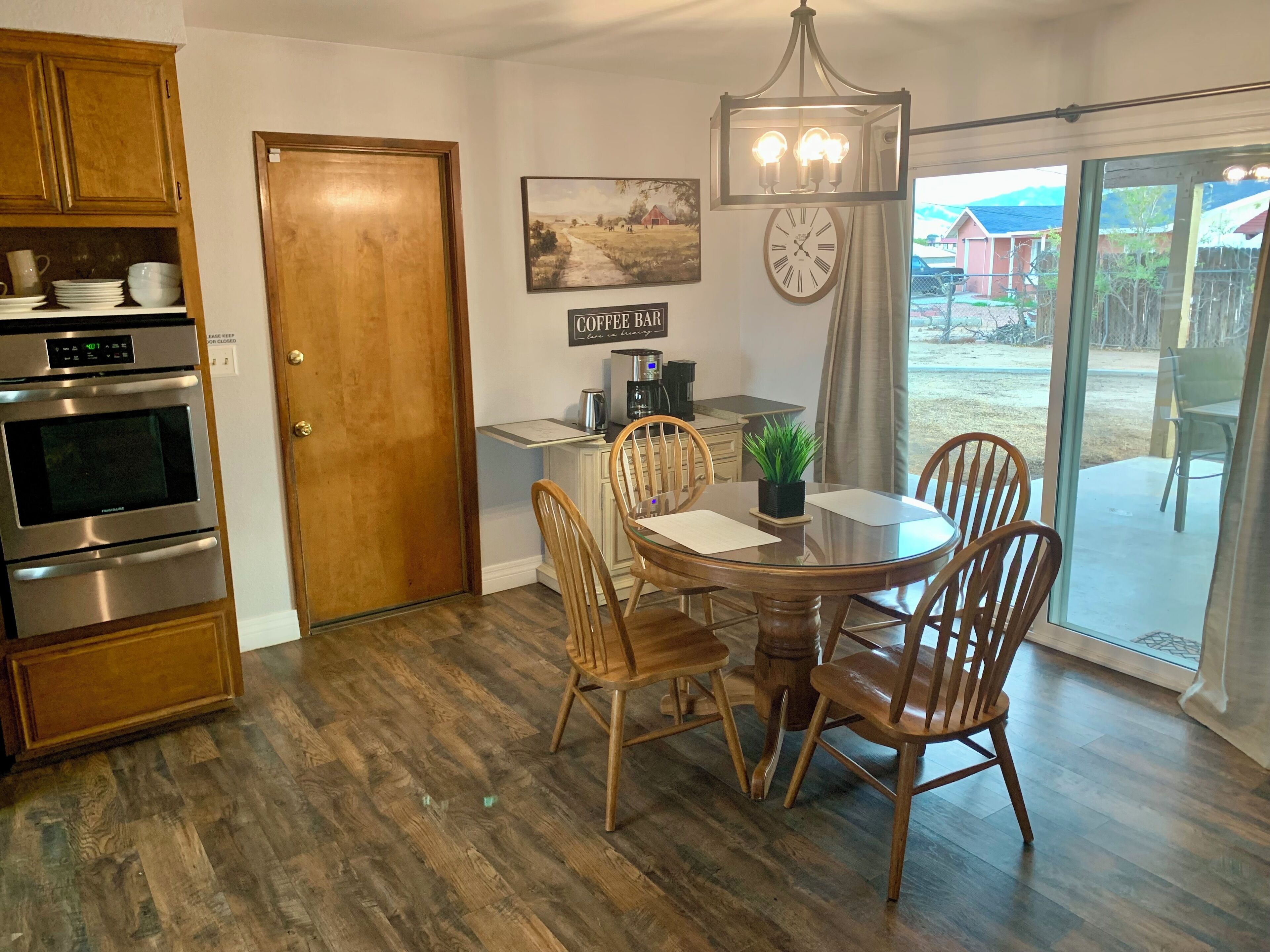 A kitchen with wooden cabinets, an oven, and a dining area with a table and chairs.