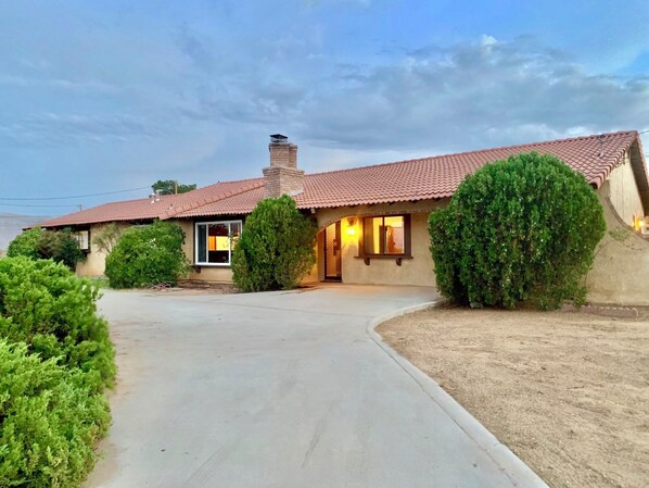 A single-story house with a red-tiled roof, a chimney, and a well-maintained front yard with shrubs. - 🌵 “Mountain View 2BR Country Home -Netflix – Spacious (Hesperia)