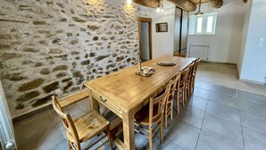 Une salle à manger rustique avec une table et des chaises en bois, des murs en pierre et un plafond en pente avec des poutres apparentes.