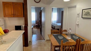 A spacious kitchen with wooden cabinets, a dining table with chairs, and a clock on the wall. - Corfu Town Flat (Kerkira)