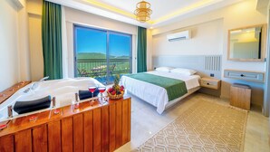 Ein modernes Hotelzimmer mit einem großen Bett, einem Holztisch mit Obstschale und Blick ins Freie.