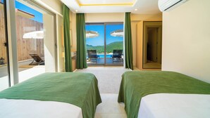 Ein Hotelzimmer mit zwei Betten, Blick auf einen Pool und Berge sowie eine Schiebetür zu einem Außenbereich.