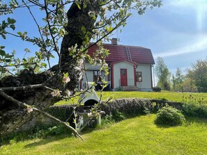 A house with a red roof, white walls, and a stone wall in front. - 6 Person Holiday Home in Kristdala (Kristdala)