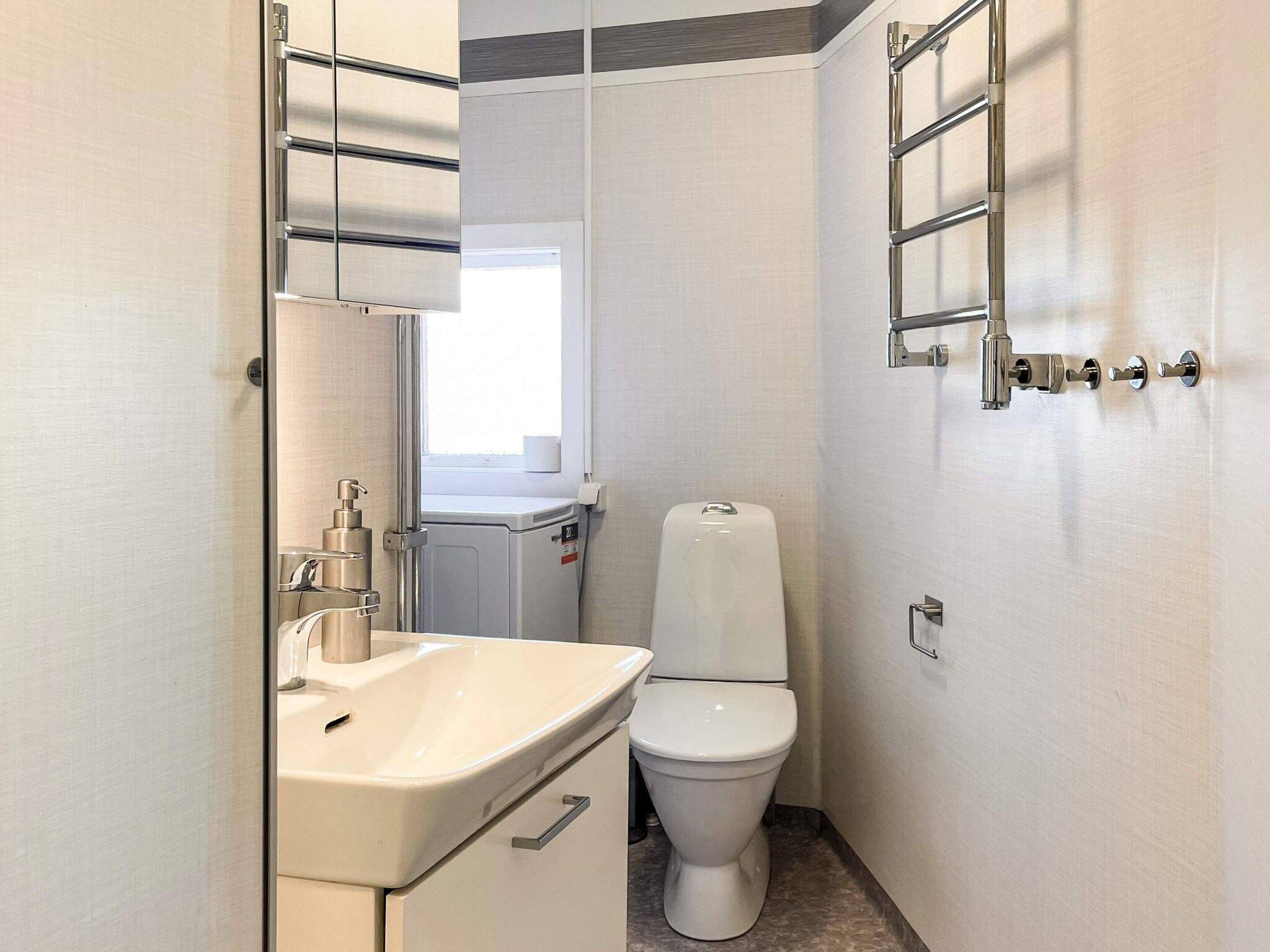 Un baño pequeño con lavamanos, inodoro y ventana que proporciona luz natural.