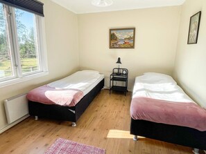 A room with two single beds, a small table with a lamp, a picture on the wall, and a window with a view of greenery. - 6 Person Holiday Home in Kristdala (Kristdala)