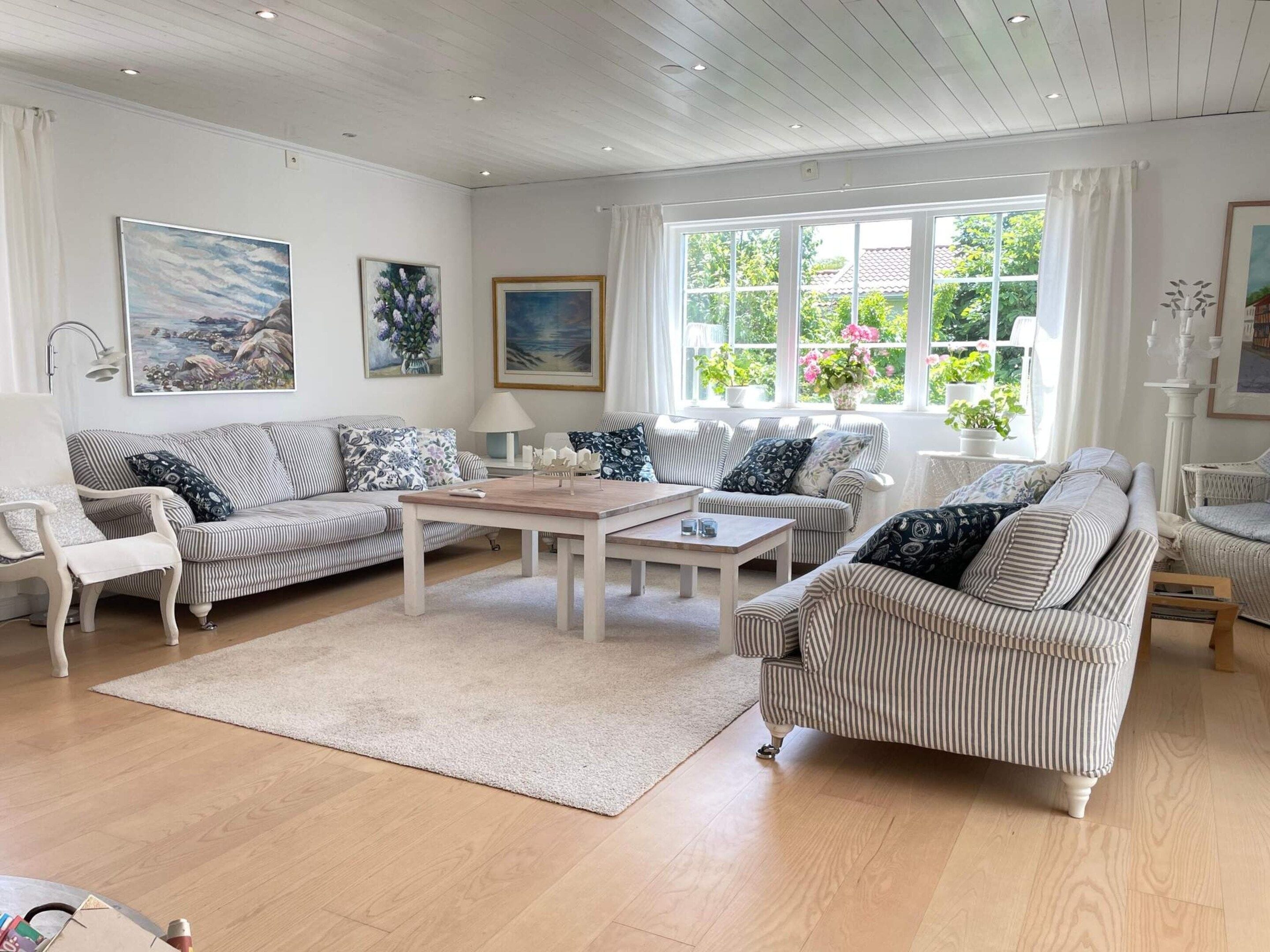A living room with striped sofas, a coffee table, and artwork on the walls.