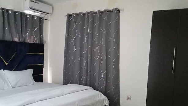 A bedroom with a bed, a wardrobe, and an air conditioning unit. - YP-MADE SUPERB VILLA featuring 2 and 1-bedroom apartments, (Ibeju Lekki)