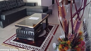 A modern living room with a black sectional sofa, a glass-top coffee table, and a decorative plant arrangement. - YP-MADE SUPERB VILLA featuring 2 and 1-bedroom apartments, (Ibeju Lekki)