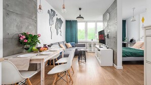 Ett modernt vardagsrum med matplats, soffa, TV och säng.