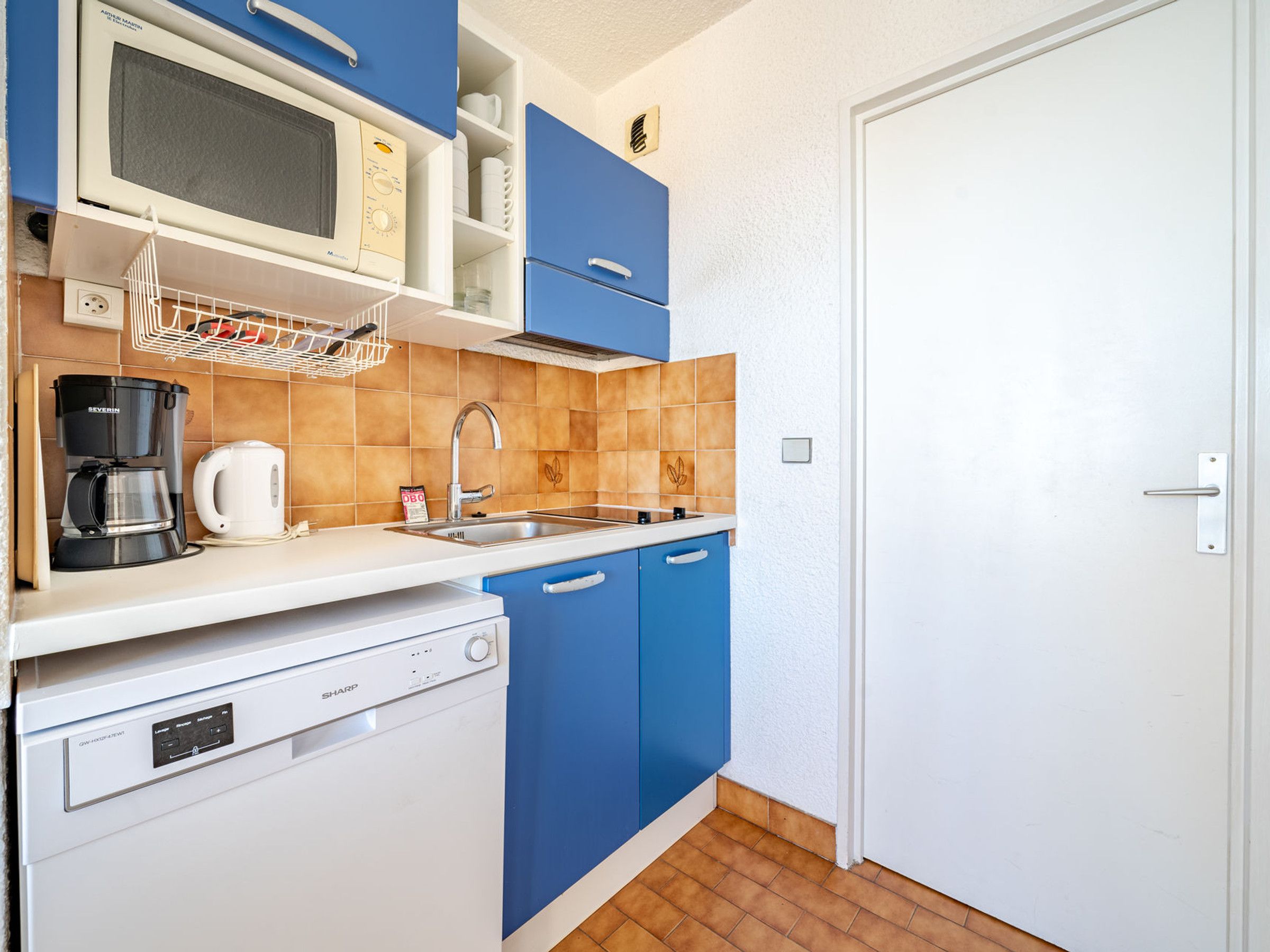 A compact kitchen with a microwave, coffee maker, and dishwasher.