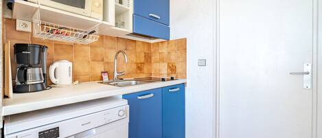 A compact kitchen with a microwave, coffee maker, and dishwasher.