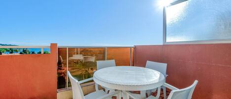 A round table with white chairs on a tiled patio.