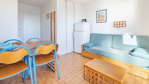Ein kompakter Wohnbereich mit Essplatz, einer Couch und einem Kühlschrank.