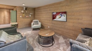 A modern living room with a wooden wall, a round coffee table, and a sofa.
