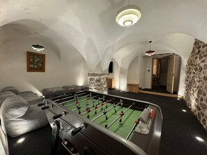 Ein Raum mit einem Kicker, einer Couch und einer Steinwand.