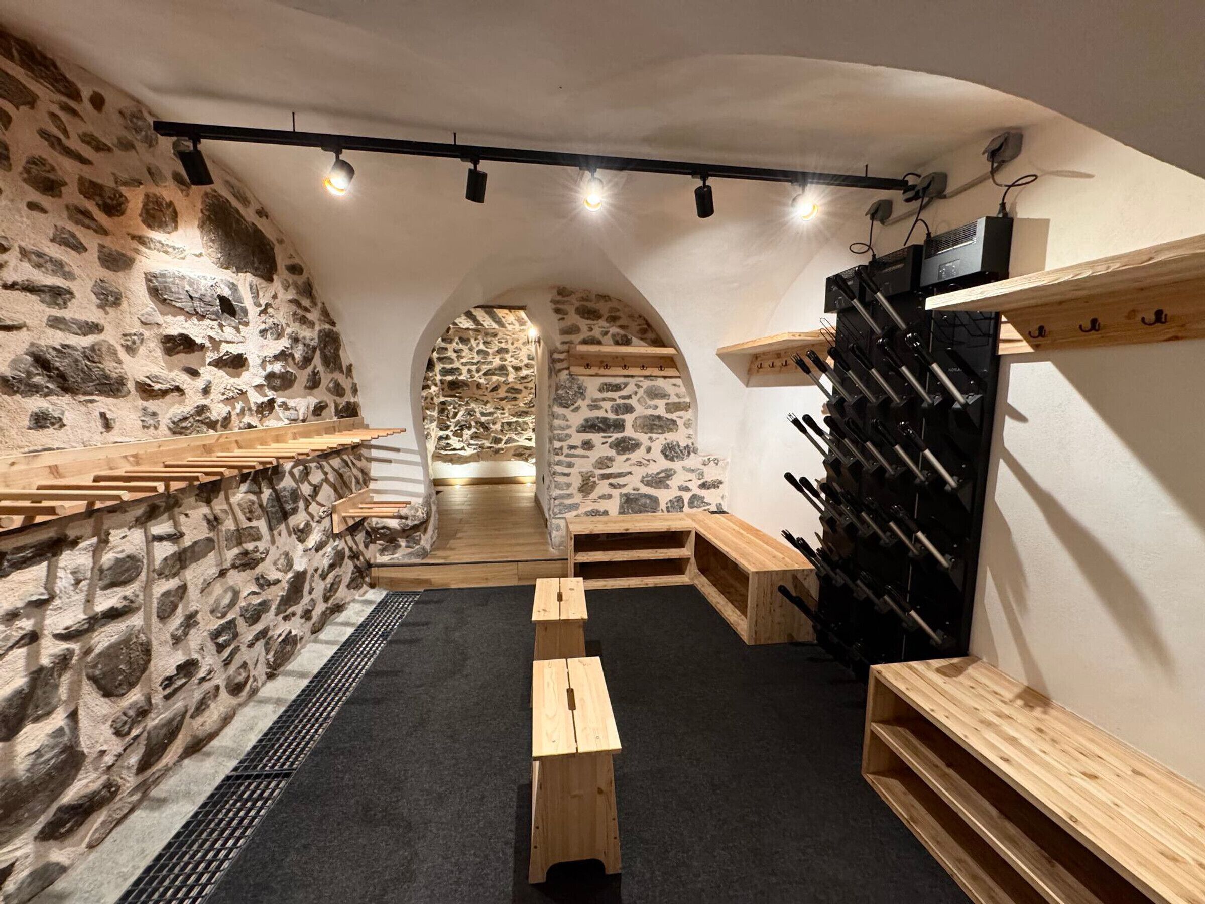 A wine cellar with stone walls, wooden benches, and a wine rack.
