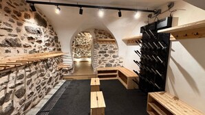 A wine cellar with stone walls, wooden benches, and a wine rack.
