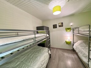 Une chambre avec deux lits superposés, un bureau et une chaise.