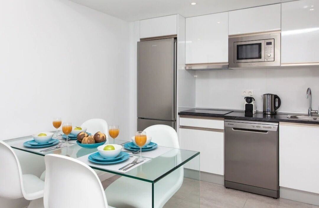 Une cuisine moderne avec des meubles blancs, un réfrigérateur en acier inoxydable, un four à micro-ondes et un lave-vaisselle.