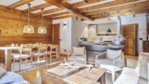 Interior rústic d'una cabana amb zona de menjador, cuina i espai d'seure.