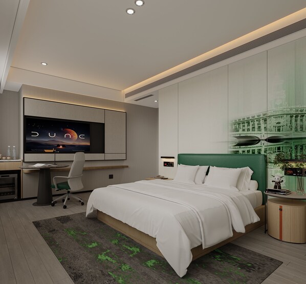 A modern hotel room with a large bed, a desk with a chair, a television, and a green accent wall.