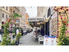 A street view of a restaurant named RISTO PIZZA with outdoor seating and a menu board visible. - Hotel Amadeus (Rome)