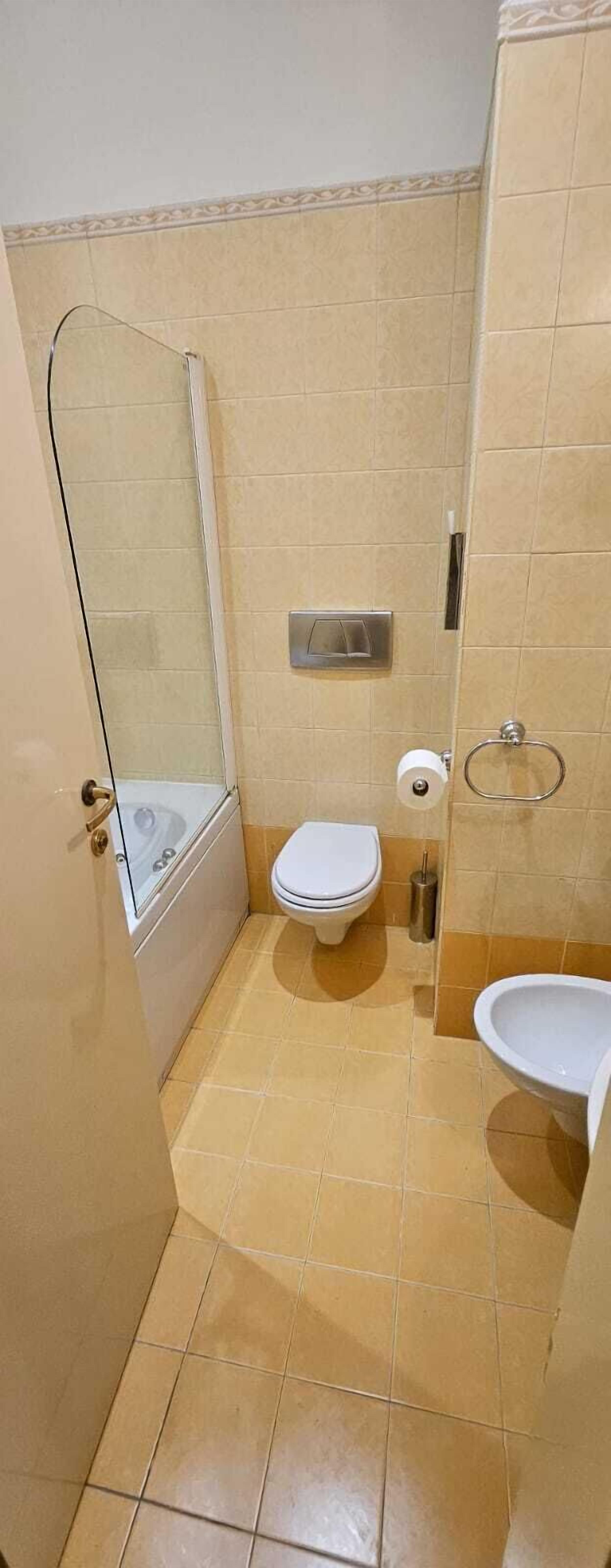 A small bathroom with a toilet, a bidet, and a glass shower enclosure.