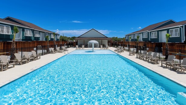 Una piscina con sillas de descanso y un edificio al fondo.