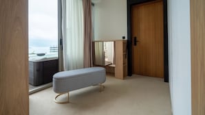 Habitación de hotel moderna con un ventanal grande, una puerta de madera y un banco.