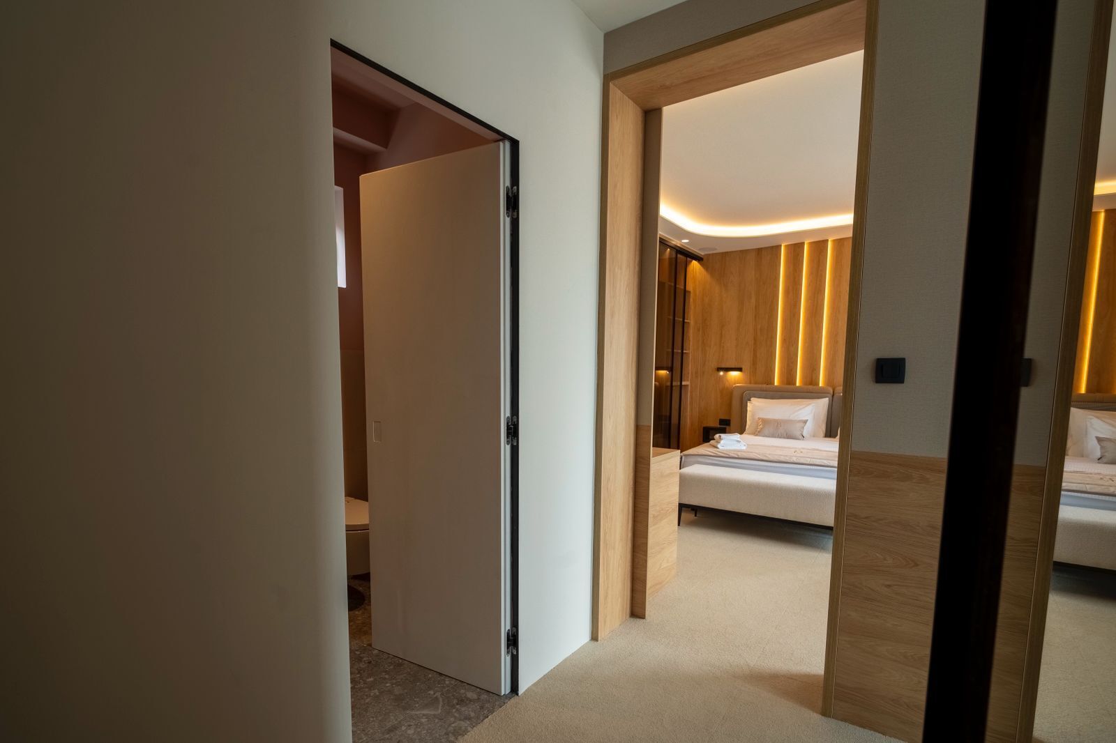 Moderni hotellihuone, jossa on sänky, yöpöytä ja pieni sivupöytä.