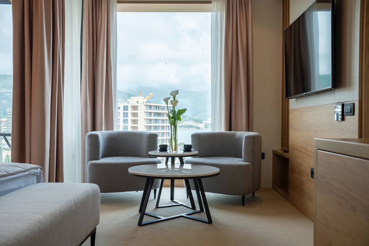 Una habitación de hotel moderna con un sofá, una mesita redonda y un televisor montado en la pared.