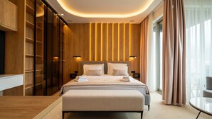 Una habitación de hotel moderna con una cama grande, armario empotrado y una mesa de cristal.