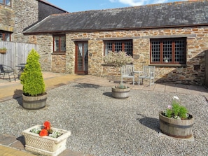 A stone building with a gravel courtyard, wooden benches, and potted plants.