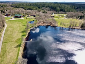 Vue aérienne d’une propriété au bord du lac, avec un quai, un petit bâtiment et une route.