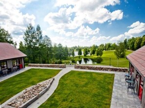 A landscaped outdoor area with a paved walkway, a small pond, and a building with outdoor seating.