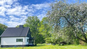 A house with a sloped roof, a small porch, and a lawn with scattered flowers. - 5 Person Holiday Home in Stehag (Stehag)