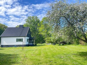 A house with a sloped roof, a small porch, and a lawn with scattered flowers. - 5 Person Holiday Home in Stehag (Stehag)