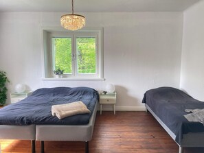 A bedroom with a double bed, a bedside table, a nightstand, a window with a view of greenery, and a chandelier. - 5 Person Holiday Home in Stehag (Stehag)
