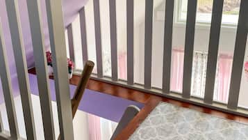 A wooden staircase with a purple mat at the bottom, leading to a room with a window.