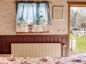 A bedroom with a bed, a window with curtains, a radiator, and a view of the outdoors. - 6 Person Holiday Home in Hemse (Hemse)