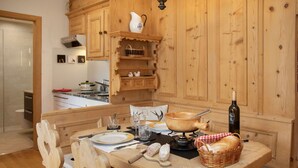 A wooden dining table set with plates, cutlery, and a bottle of wine, surrounded by wooden chairs and a basket of bread. - Nice apartment for 2 guests with pool, WIFI, TV, patio, pets allowed and panoramic view (Falera)