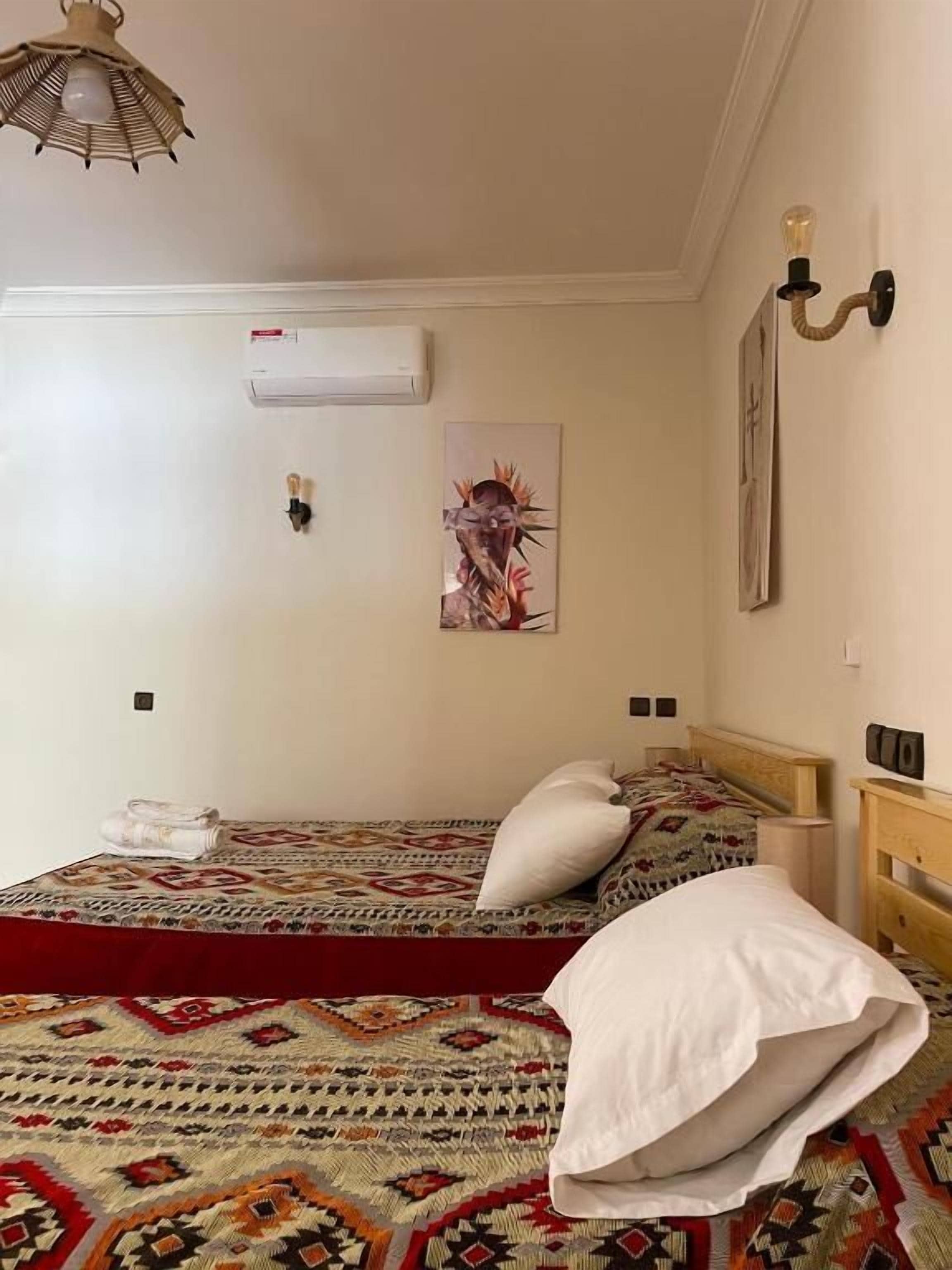 Une chambre à coucher comprenant un lit, un climatiseur fixé au mur, une œuvre d’art murale et un luminaire.