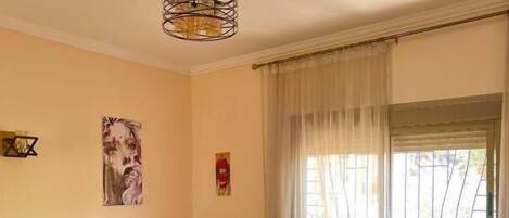 A hotel room with a sofa, a bed with a patterned bedspread, a coffee table, and a window with curtains.