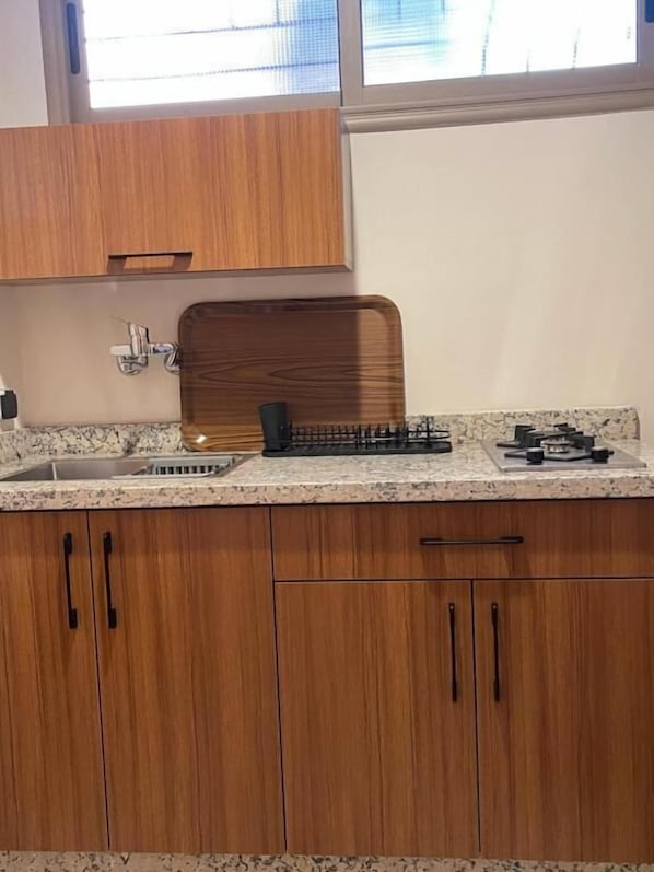 A kitchen with wooden cabinets, a granite countertop, and a window above the sink. - Dyafat Abla (Ouarzazate)