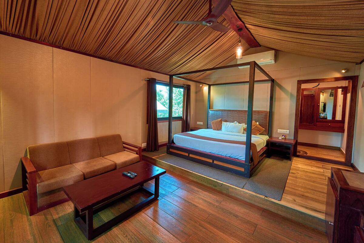 Une chambre à coucher avec un lit à baldaquin, un canapé, une table basse et un ventilateur de plafond.