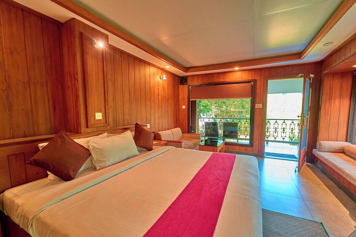 Une chambre d’hôtel avec un grand lit, des boiseries, une télévision et un balcon avec vue.
