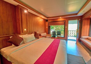 A hotel room with a large bed, wooden paneling, a television, and a balcony with a view.